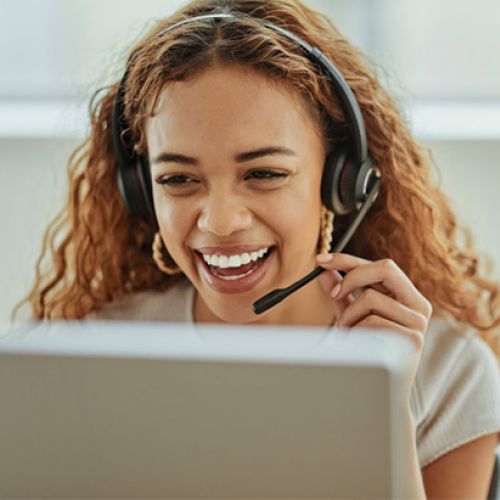 Smiling woman with headset taking a call on her laptop